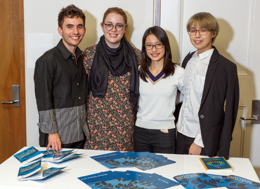 Four undergraduate students pose for a photo at the reception desk for an awards ceremony