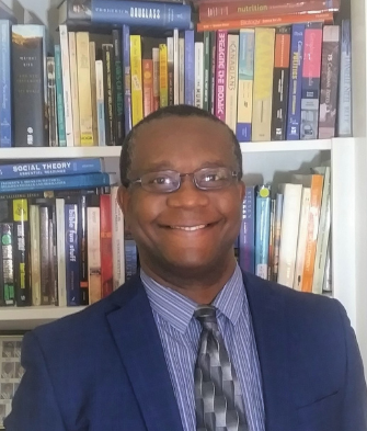 Ronald Charles smiles with bookcase behind him 